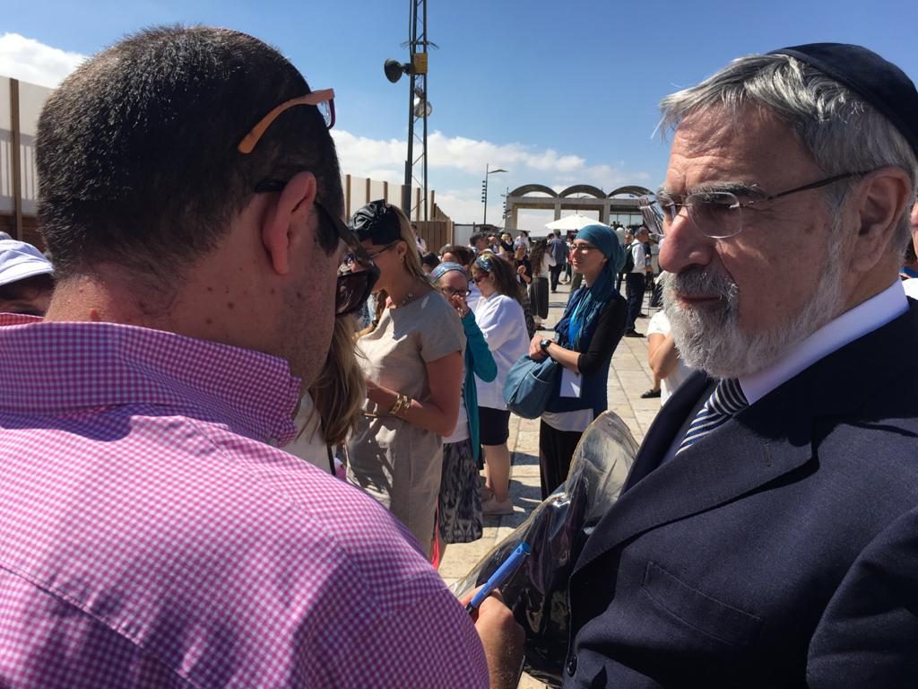 צביקה קליין, בגבו למצלמה, מראיין את הרב יונתן זקס ברחבת הכותל המערבי